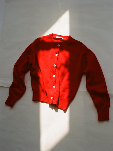 Red cardigan with a crewneck collar and round white buttons